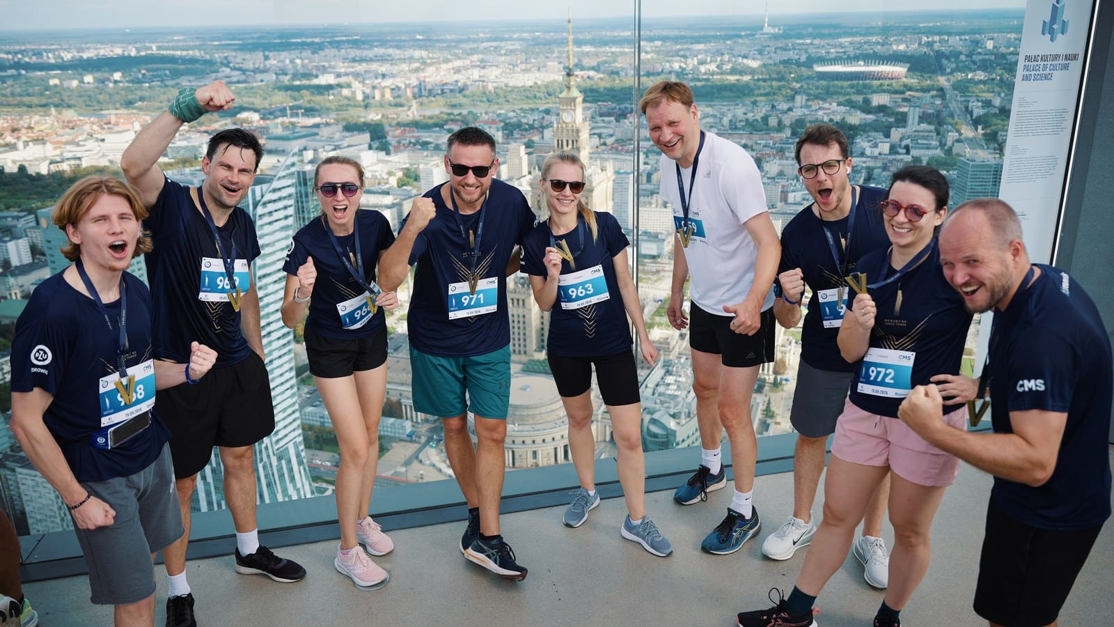 HB&nbsp;Reavis team celebrating with medals at the top of Varso Tower, Palace of Culture and Science and Warsaw skyline behind them