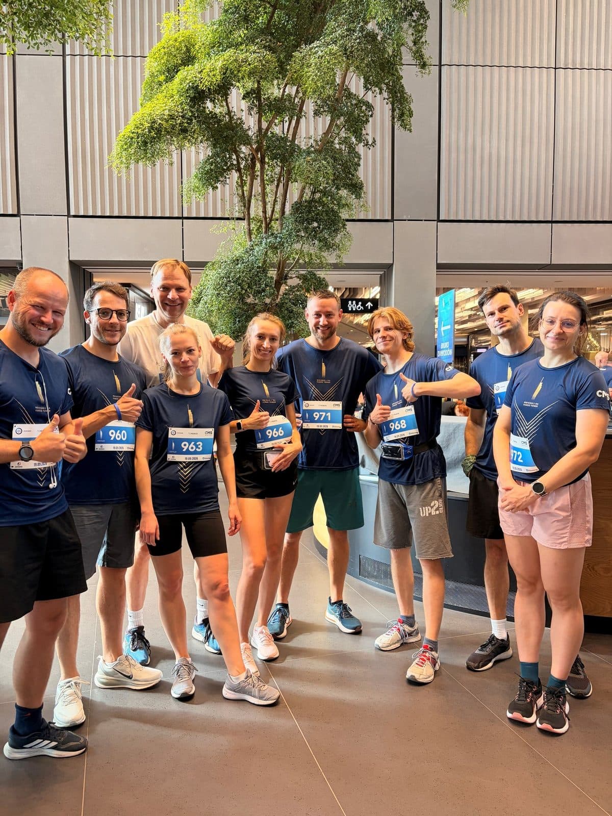 HB&nbsp;Reavis team in navy race shirts with start numbers before the Varso Tower Run in the Varso Tower lobby